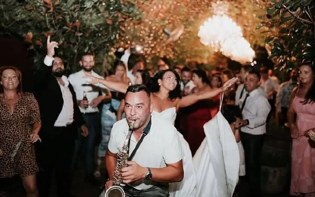 Orget Sax at a wedding entrance surrounded by sparklers and guests